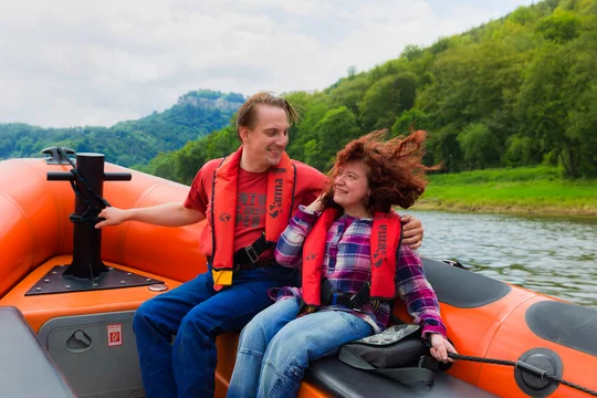 Rollstuhlfahrerin auf dem Powerboot auf der Elbe in der Sächsischen Schweiz. Im Hintergund ist die Festung Königstein zu sehen. Rollstuhlfahrerin auf dem Powerboot auf der Elbe in der Sächsischen Schweiz