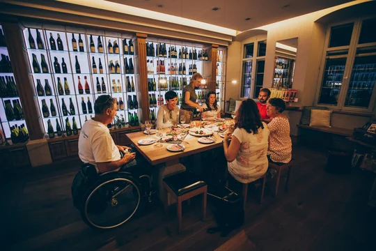 Auf dem Weingut Maikammer können Gäste mit und ohne Einschränkungen die Weinkreationen in geselliger Runde verkosten. Foto: Weingut Maikammer Gruppe bei Tisch