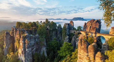 das maechtige Basteimassiv in der Saechsischen Schweiz mit der weltberuehmten Bruecke, im Hintergrund der Tafelberg Lilienstein 