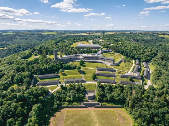 Beeindruckender Gedächtnisort: Die ehemalige NS-Ordensburg ist heute sowohl Museum als auch Begegnungsstätte. Foto: Vogelsang IP Ein Luftbild der Vogelsang IP. Die beeindruckende Anlage liegt mitten im Wald.