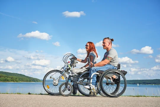 Ausgebaute Uferwege und barrierefreie Rastplätze: Das Fränkische Seenland ist ein Paradies für Handbikefahrer Zwei Handbikefahrer biken auf einem Weg am Seeufer entlang