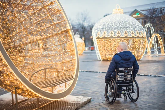 Hans-Jürgen rollt auf der Lichterwelt in Magedeburg Rollstuhlfahrer zwischen Lichtinstallationen auf einem ebenen Platz