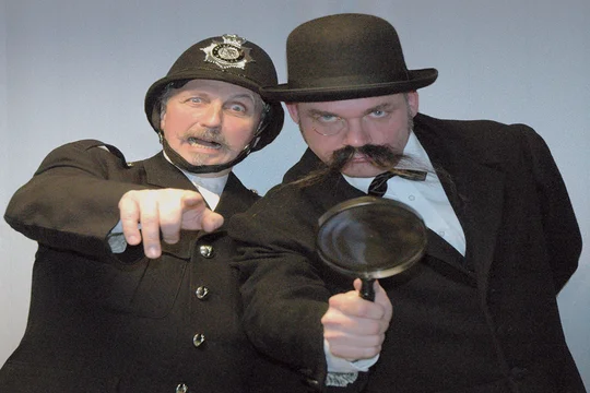 Ein englischer "Bobby" und Ermittler mit Lupe suchen nach Spuren