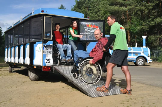 Fahrt mit der Kleinbahn Seeschlange Rollstuhlfahrer wird über die Rampe in die Kleinbahn gefahren