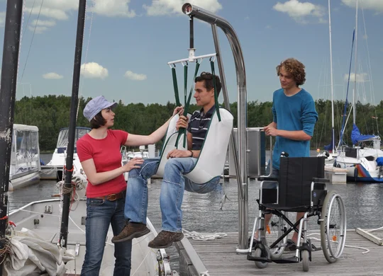 Hafencamp Senftenberger See Gast wird im Lift sicher in ein Segelboot gesetzt