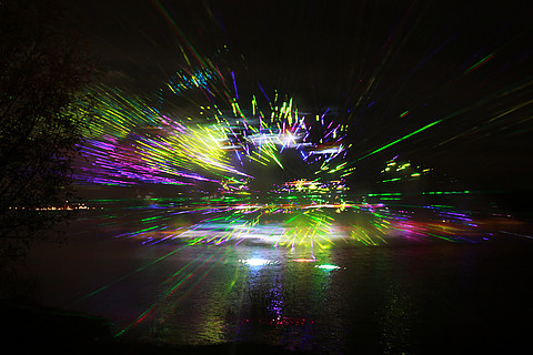 Bunte Laserlichtshow im Dunkeln spiegelt sich im Wasser