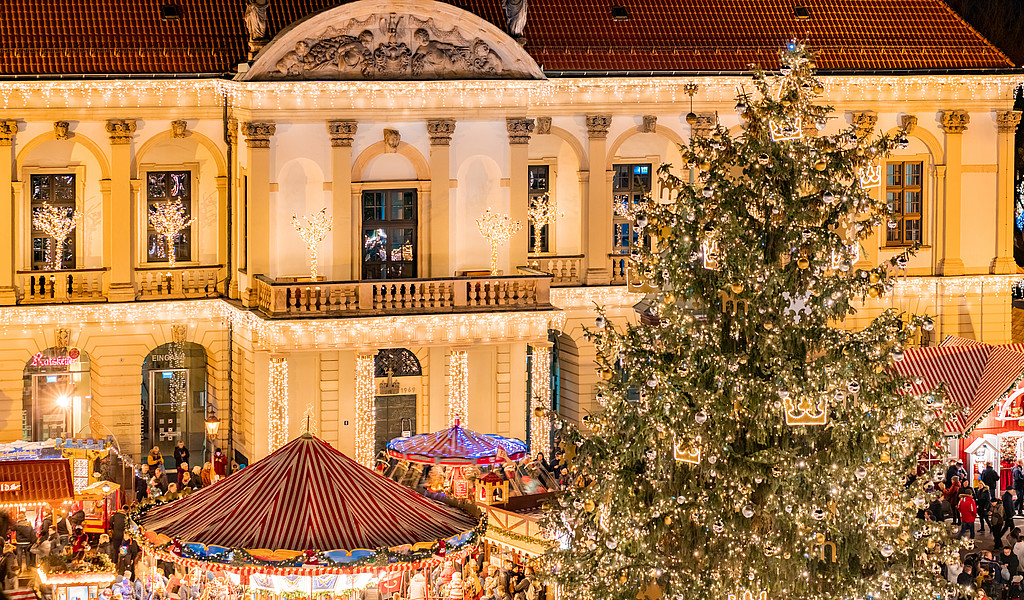 Weichnachtlich geschmückter und Beleuchteter Weihnachtsbaum im fordergrund des Rathauses